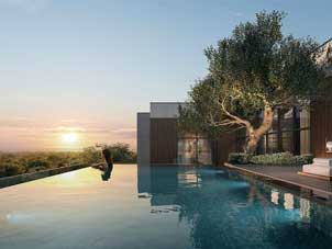 A tranquil evening scene at Ghaf Woods featuring a luxury infinity pool overlooking the landscape as the sun sets.