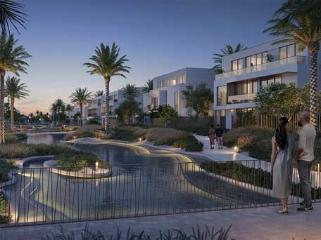 Evening view of the Oasis by Emaar, featuring modern architecture, water features, and lush landscaping.